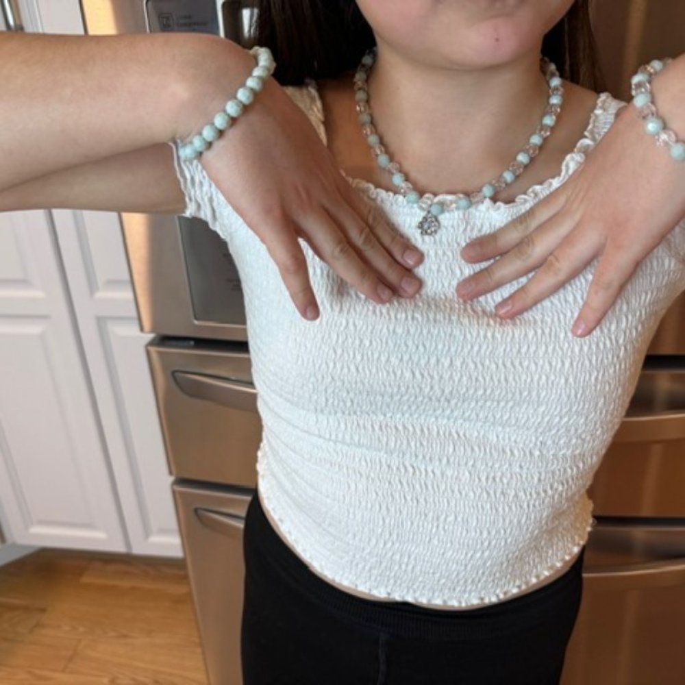 Light gray beaded necklace with two matching bracelets.